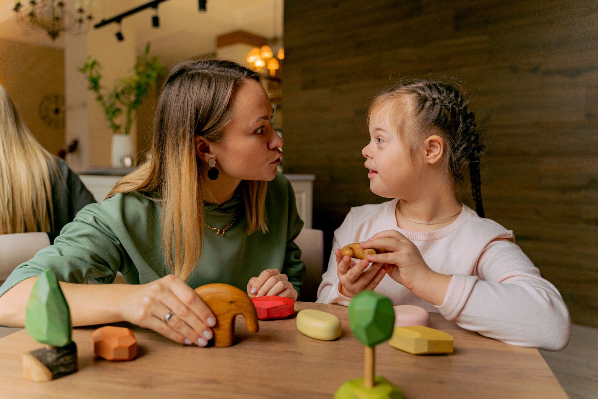 A woman and a girl face each other in conversation over coloured wooden blocks